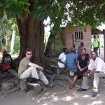 Jim, Loveness and Hassan wait under mango tree for go-ahead to install station